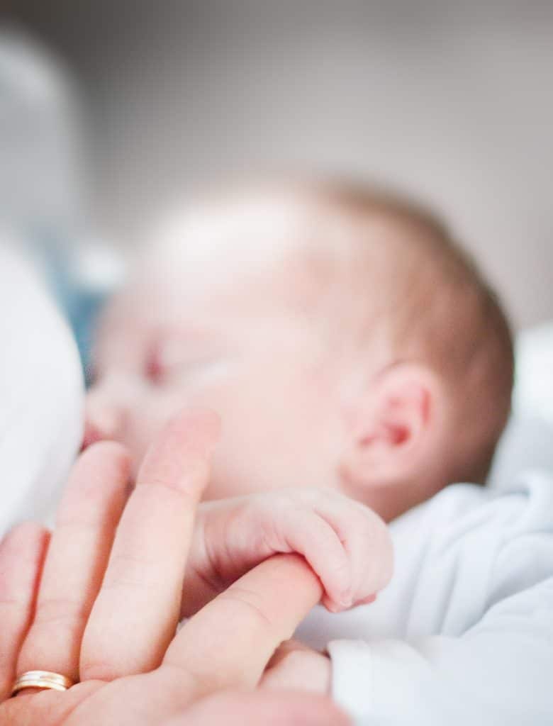 Baby holding adult person's index finger