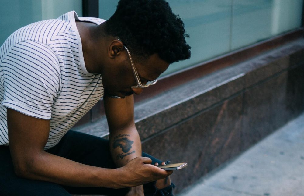 How to get over your ex blog post - Man hunched over looking at phone